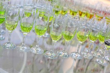 glasses with green champagne on white table