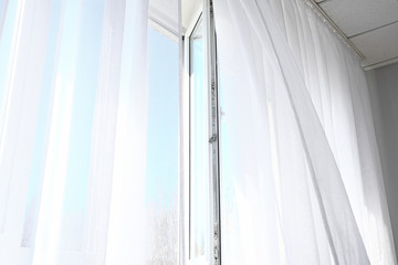 Open window with light curtains in room
