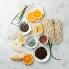 Homemade skin care and body scrubs and mask with natural ingredients aloe vera, lemon, coffee, oranges, clay, honey set up on white wooden background with flat lay