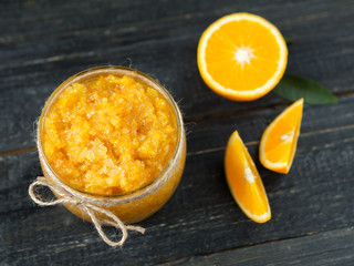 Homemade orange jam on a wooden table with pieces of fruit