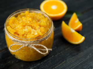 Homemade orange jam on a wooden table with pieces of fruit