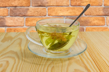 Linden flower tea in glass cup on wooden table