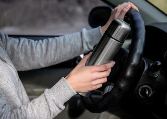 Woman with thermos driving a car