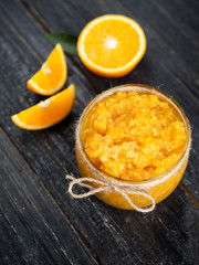 Homemade orange jam on a wooden table with pieces of fruit