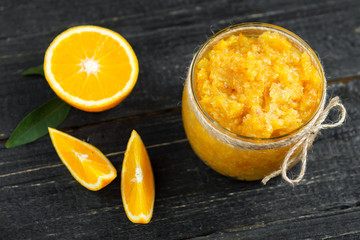 Homemade orange jam on a wooden table with pieces of fruit