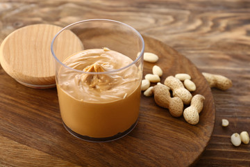 Glass of tasty peanut butter on wooden table