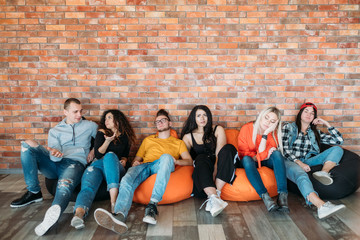 Diverse group of millennials sitting on bean bags. Bored and annoyed. Tired of dull presentation,...