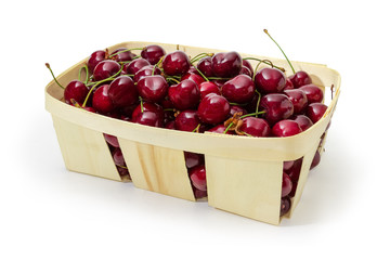 Wooden basket of dark red sweet cherries on white background