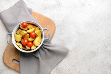Pot with tasty baked potato on grey table