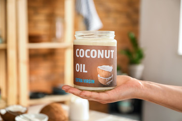 Woman holding jar of coconut oil in kitchen