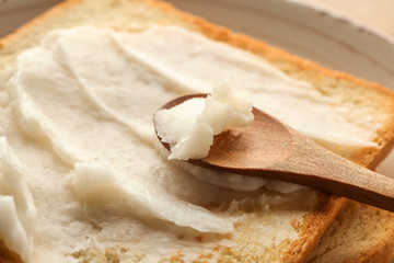 Spoon with coconut oil and tasty toasted bread, closeup