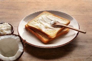 Coconut oil with tasty toasted bread on wooden table