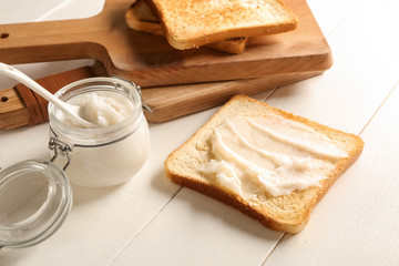 Coconut oil with tasty toasted bread on white table