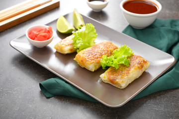 Plate with tasty fried spring rolls on table
