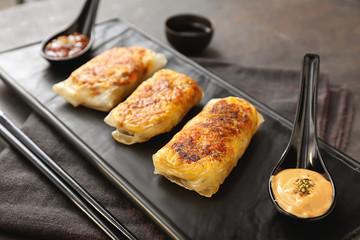 Plate with tasty fried spring rolls on table