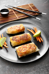 Plate with tasty fried spring rolls on table