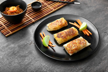 Plate with tasty fried spring rolls on table