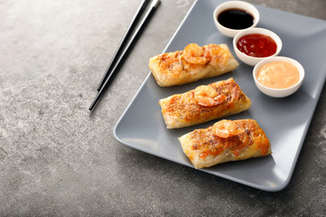 Plate with tasty fried spring rolls on table