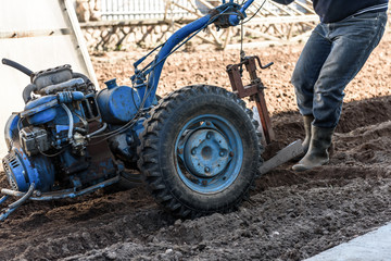 Obraz premium A man working in the field. A man plows the land with motor cultivator