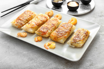 Plate with tasty fried spring rolls on table