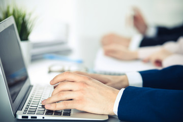 Group of business people working together in office. Man hands typing on laptop computer