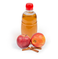 Bottle of apple cider, two fresh apples and cinnamon sticks