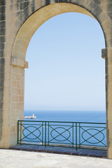 View of a lighthouse through arches in the Lower Barrakka Gardens, Valletta, Malta