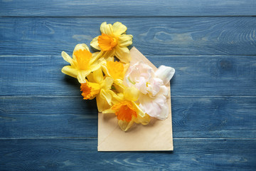 Envelope with beautiful flowers on wooden background