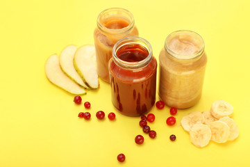 Jars with different healthy baby food on color background