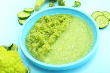 Plate with healthy baby food on color background
