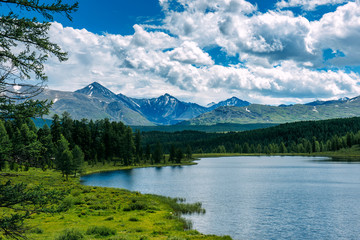 Naklejka na ściany i meble Mountain landscape, white clouds, lake and mountain range in the distance. Fantastic sunny day in mountains, large panorama. Location is in Altai, Russia.