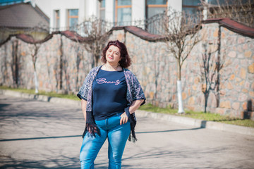 Fototapeta premium Piękna kobieta nosi sweter z dzianiny, dżinsy w przyrodzie. Moda codzienna, elegancki wygląd na co dzień. Model dla puszystych