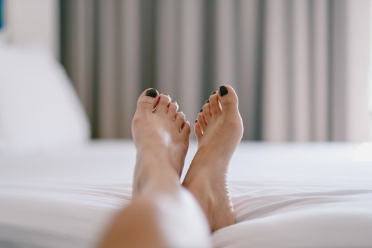 Closeup image of a woman's feet on a white bed