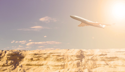 The plane in the sky over the desert. The sun shines.