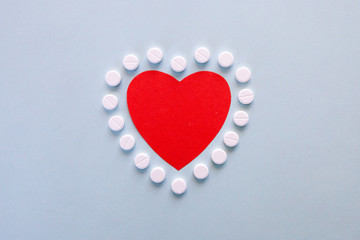 medicine, healthcare and pharmacy concept - pills and of drugs in shape of the heart and heart rhythms.