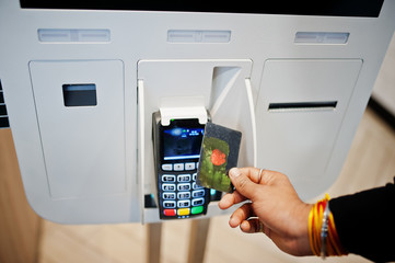 Hands of man customer at store place orders and pay by contactless credit card through self pay floor kiosk for fast food, payment terminal. Pay pass.