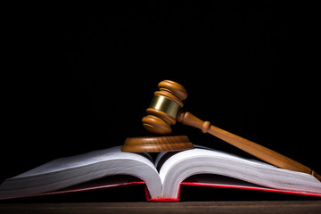 Legal law and justice concept. Judges gavel with soundboard on big opened law book against black...