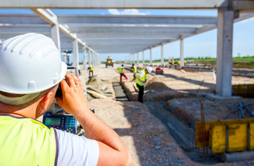 Civil engineer, geodesist is working with total station on a building site