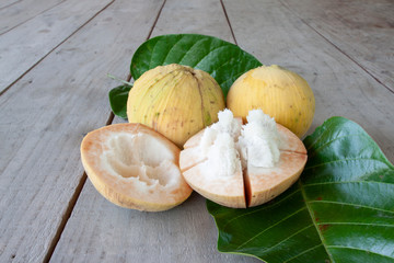 Half cut ripe Santol or Sentul fruit (Sandoricum koetjape) with leaf on wooden table.