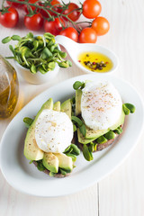 Avocado toast, cherry tomato on wooden background. Breakfast with toast avocado, vegetarian food, healthy diet concept. Healthy sandwich with avocado and poached eggs.