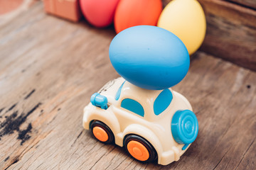 Fototapeta premium Easter egg and toy car on wooden background,