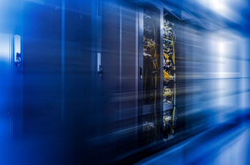 Server racks row in big data center with depth of field in cool blue tone and motion effect