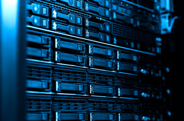Close up blade server equipment rack in big data center with blurred side frame cold blue tone