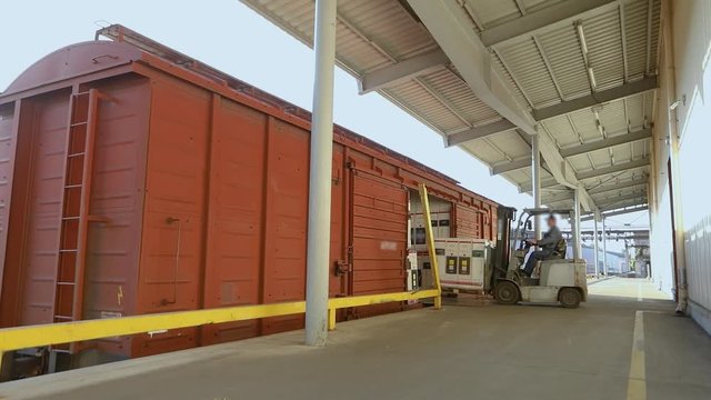 Forklift delivers the cargo to the train car. Loading wagon freight train