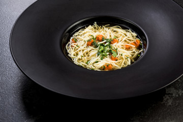 Homemade chicken soup served in dark plate