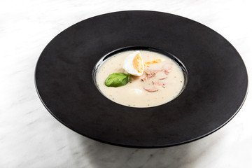 Homemade sour soup served with egg on dark plate