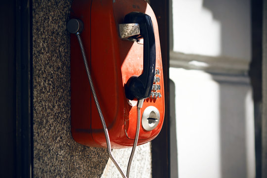 Street red retro telephone, available for everyone, which illuminates the solar bright light.
