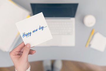 Woman clerk sitting holding note paper sticker with Happy new day phrase. Business concept. Concept.