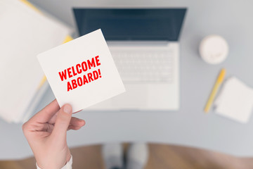 Woman clerk sitting holding note paper sticker with welcome aboard phrase. Business concept. Concept.