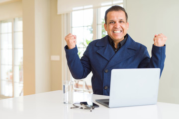 Middle age business man working using laptop celebrating surprised and amazed for success with arms raised and open eyes. Winner concept.